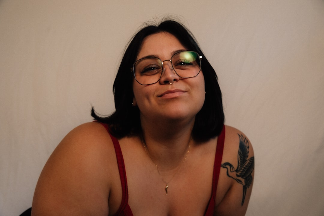 A woman with glasses and tattoos smiles. — Foto por Brooke Balentine na Unsplash