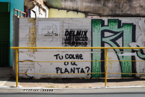 Graffiti and advertising adorn a weathered wall. — Foto por Daniel Ribeiro na Unsplash