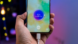 a person holding a cell phone with a charger in their hand — Foto por Amanz na Unsplash